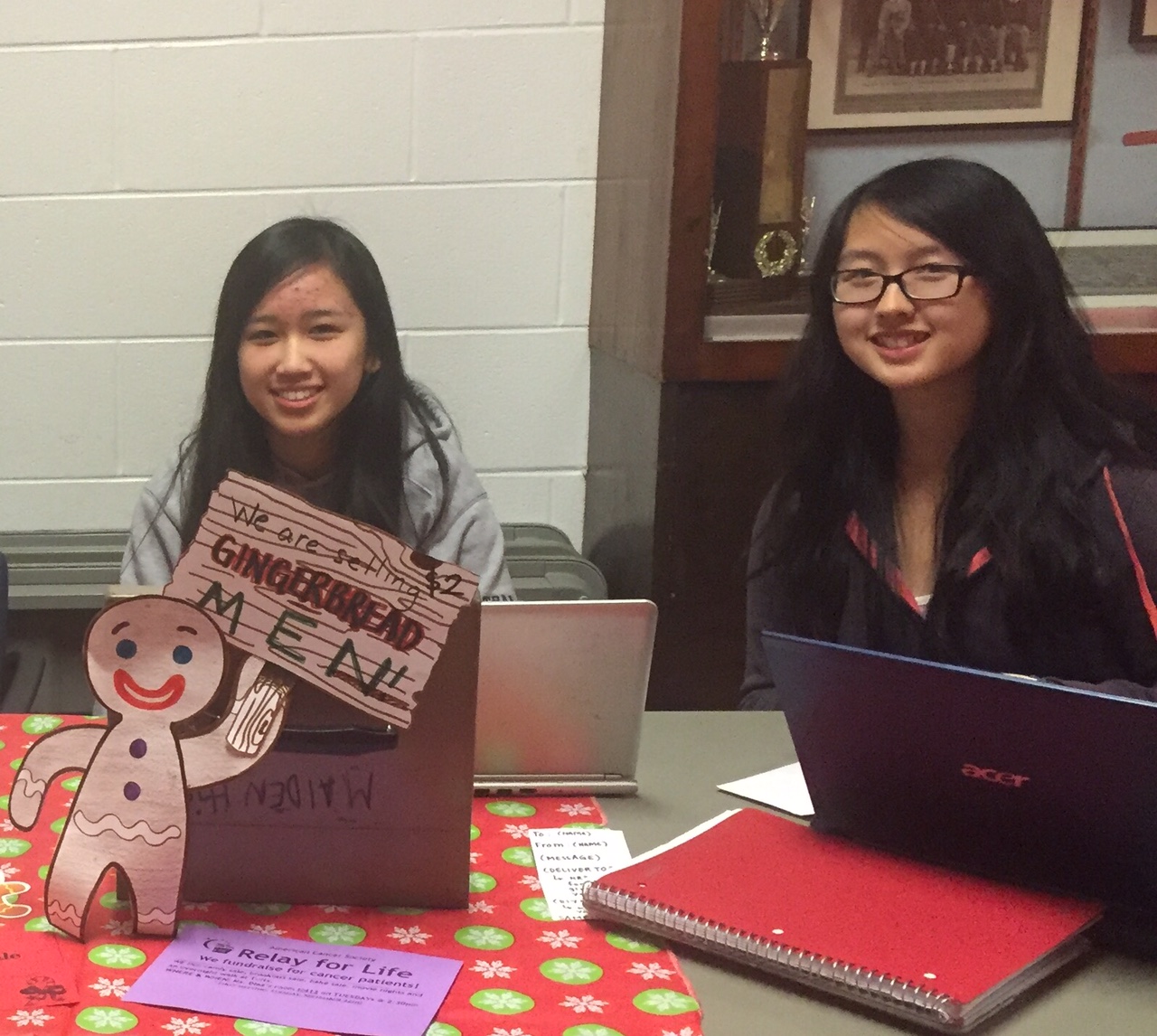 Gingerbread fundraiser table outside MHS cafaterias. Left: Linda Tran, Treasurer. Right: Daria Lee, President. Photo by Sydney Stumpf.