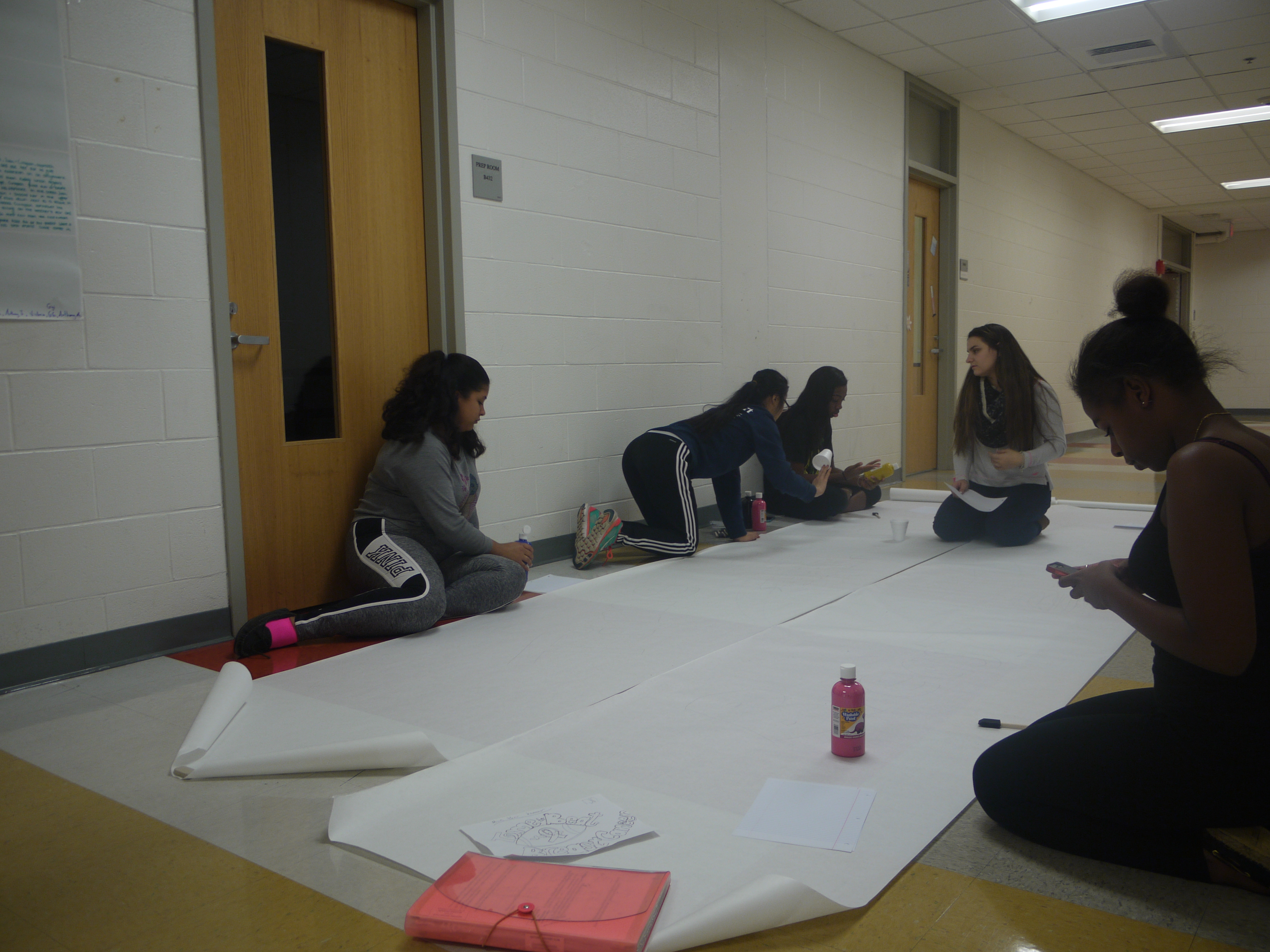 Malden Against Cancer members making the banner for the pink-out football game. Photo taken by Josandy Jeune. 